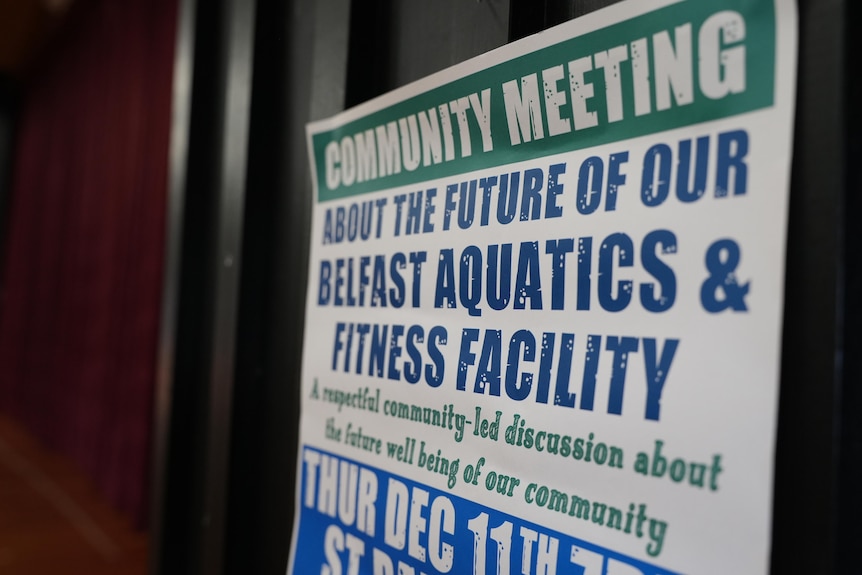 A blue and green sign announcing a commuity meeting to dicuss a local pool. 