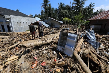 Residents walk among large piles of wood that were swept away by the flood waters in a village in the Meureudu area of Indonesia.