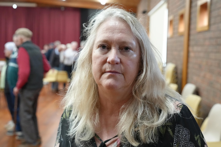 A middle aged woman in a red cardigan. 