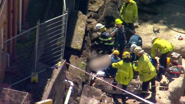 Crews pull the 19-year-old from beneath the collapsed retaining wall.