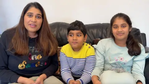 BBC Pooja (left) and her son (middle) and daughter (right) on the sofa.