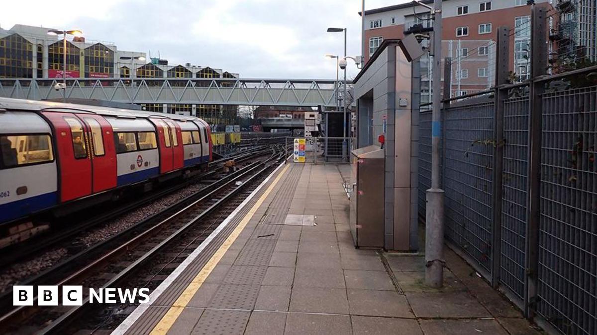 Platform at Stratford shows Jubilee line train on left with bridge ahead and housing in the background