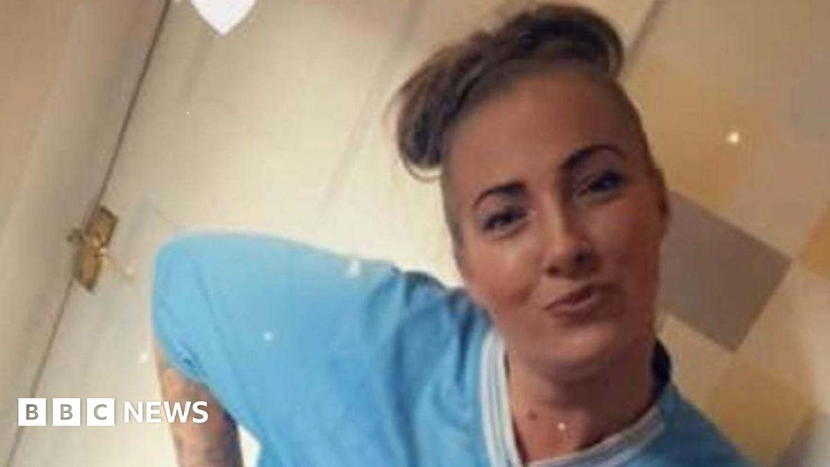 A young woman with tied-up blonde hair smiles for the camera, wearing a blue T-shirt with a while collar.