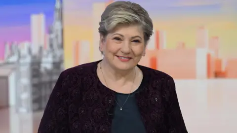 Labour MP Emily Thornberry wears a red jacket and dark top.
