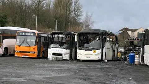 BBC Four buses, badly burnt out. One of the left has a school bus sign