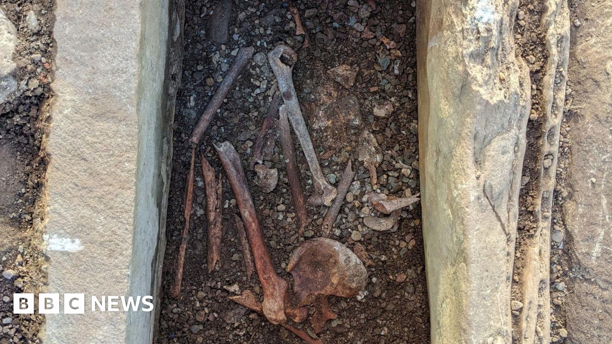 A burial cist, with bones visible - they are in the process of being excavated