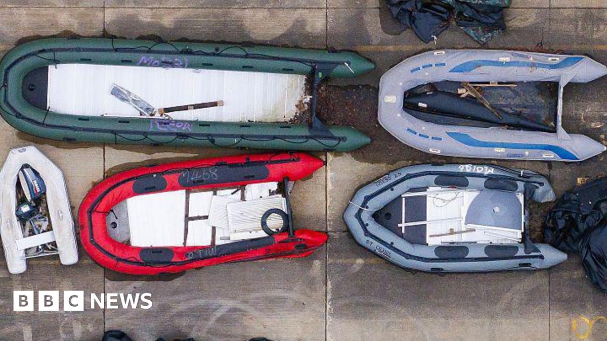 A brown NC500 sign post which says it is 27 miles to Ullapool next to a country road with hills in the background.