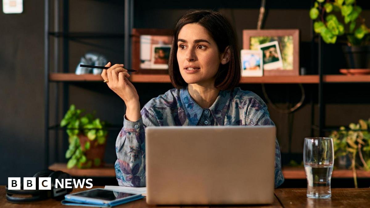 Female entrepreneur remote working, holding pen and contemplating, sitting at table, WFH