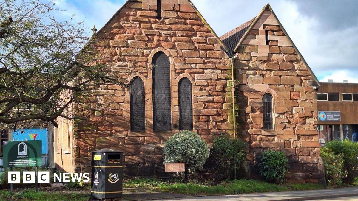 A red-brick building, which is home to Maggs Day Centre. Several bushes and a black bin are outside the building.