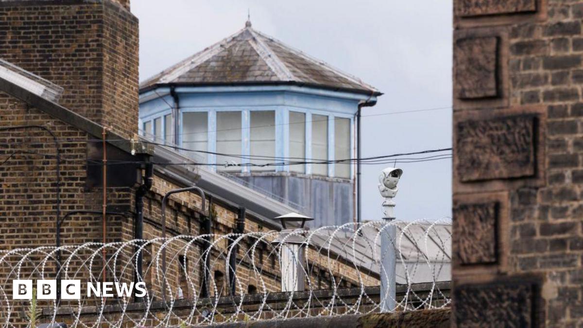 A security camera and barbed wire outside HMP Wandsworth prison in London.