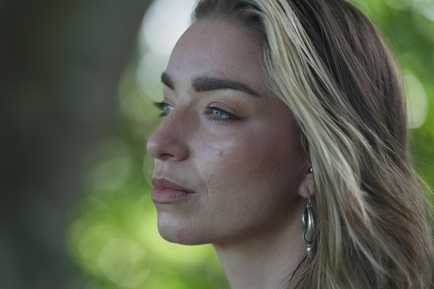 Close up of a woman's face with earrings and flowing blonde hair.