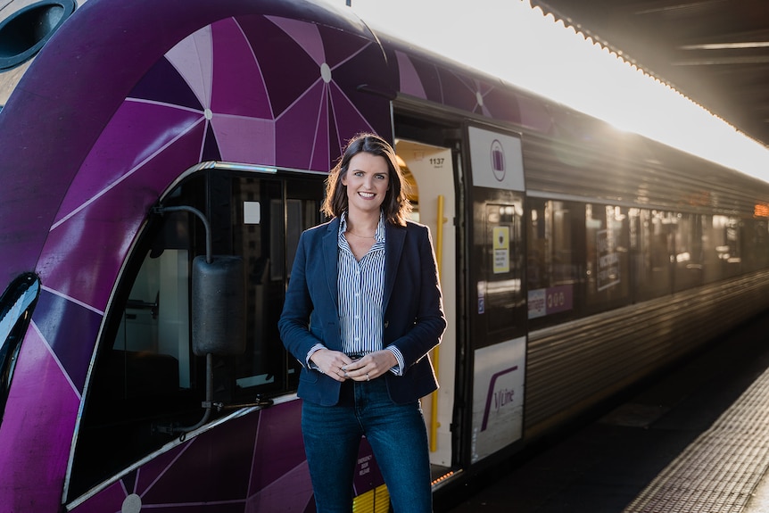 A picture of a woman standing in front of a train.