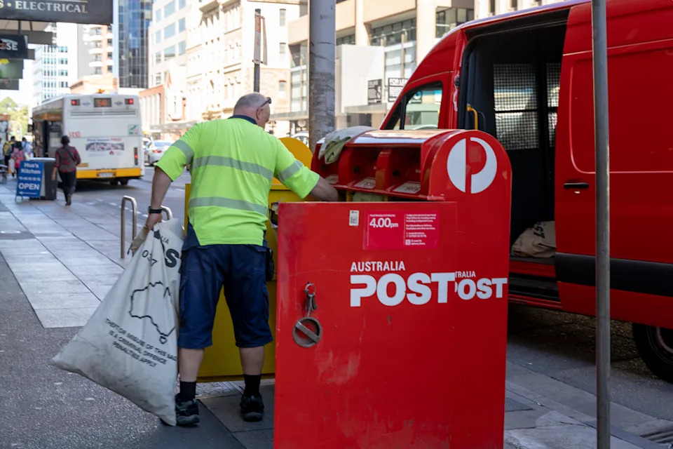 An Australia Post postman collecting the post from a mail box.
