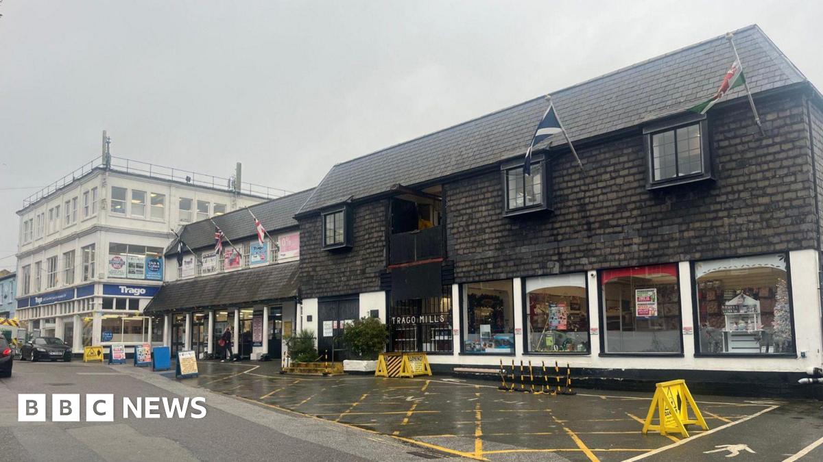 The front of the Trago Mills store that is black and cream in colour. There is signage at the front of the store which flags flying while hanging from the building.