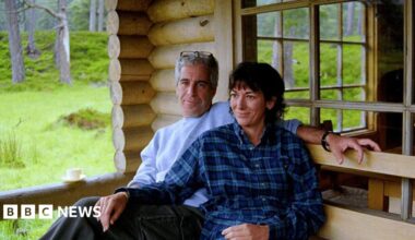 An undated photo released by the US justice department shows Jeffrey Epstein and his co-conspirator Ghislaine Maxwell seated close together outside a wooden home, appearing to be a cabin of some kind in a wooded area.