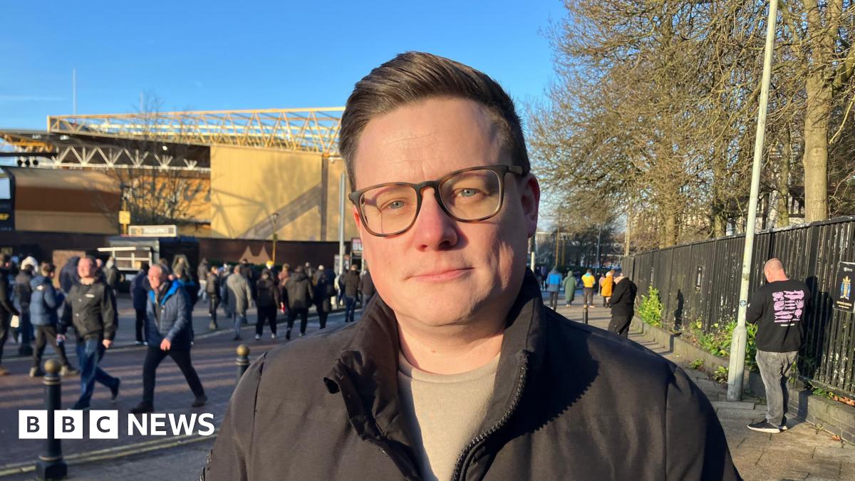 Jeff Shi is wearing a white shirt and grey blazer and looking directly at the camera