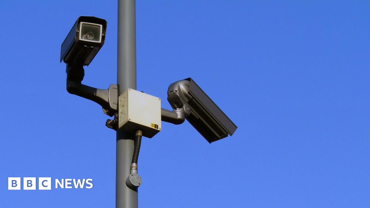 Two CCTV surveillance cameras on a lamppost against a bright blue sky