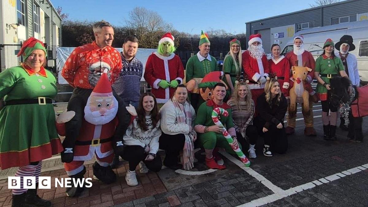A group of people in an industrial estate car park wearing Christmas costumes.