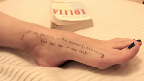 House Oversight Committee a woman's foot laying across a bed with a quote from Lolita written on it "She was Lo, plain Lo, in the morning, standing four feet ten in one sock" with the Lolita book in the background