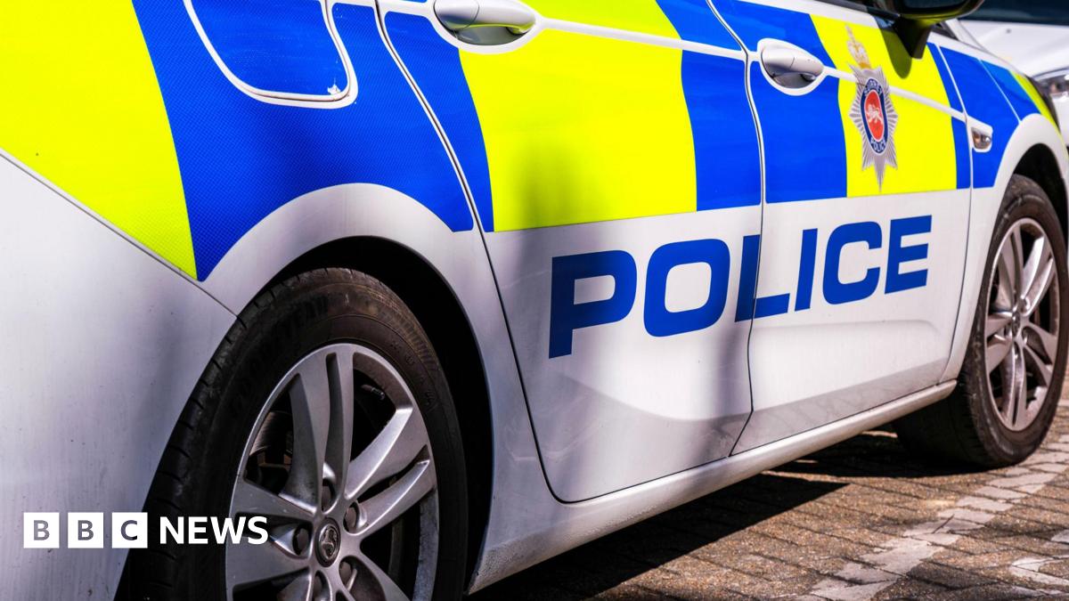 A yellow and blue police car with the word police in bold font on the side. Above the writing is a Surrey Police logo.