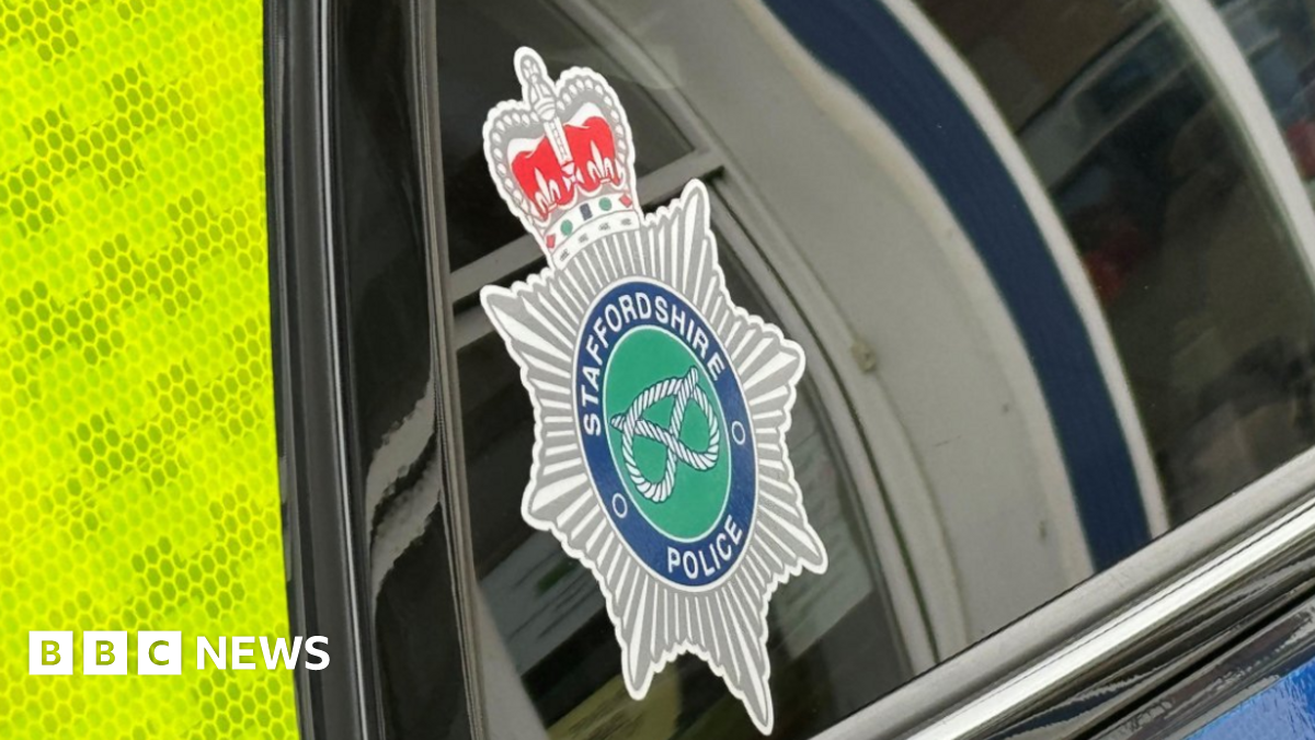 The side of a police vehicle, with a crest of Staffordshire Police in the corner of the window