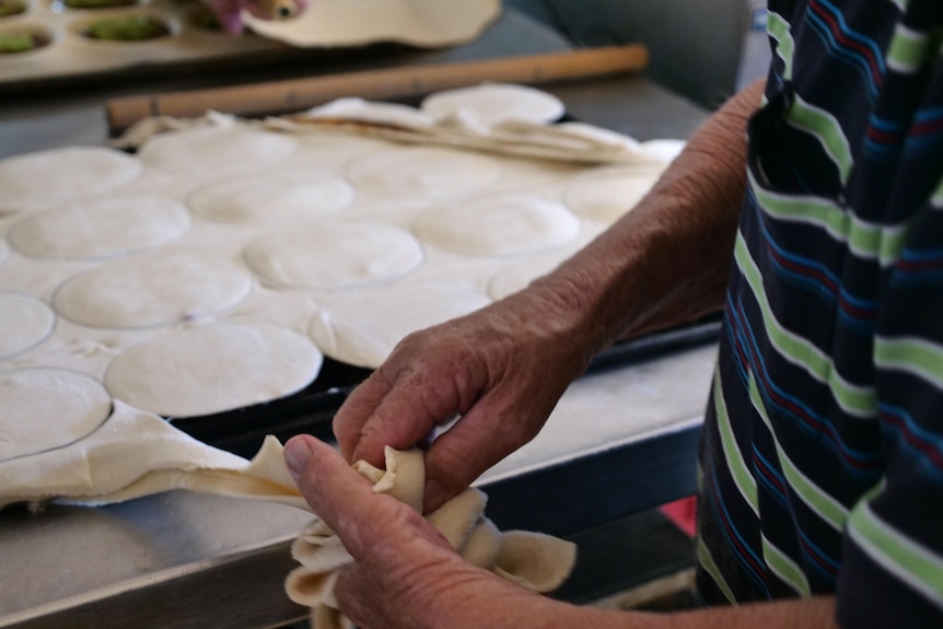 Two hands pulling at pastry. 