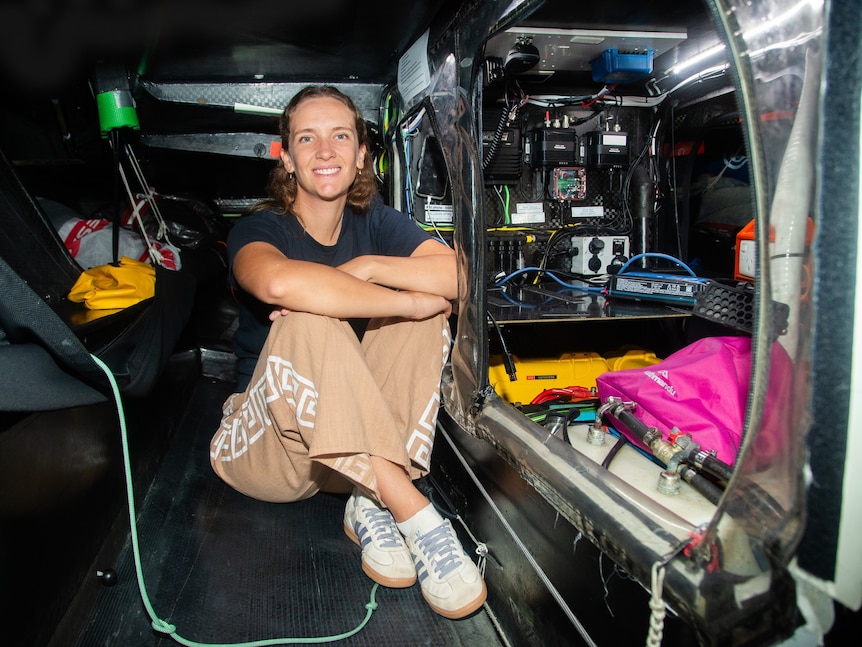A woman sitting down inside a boat's hull.