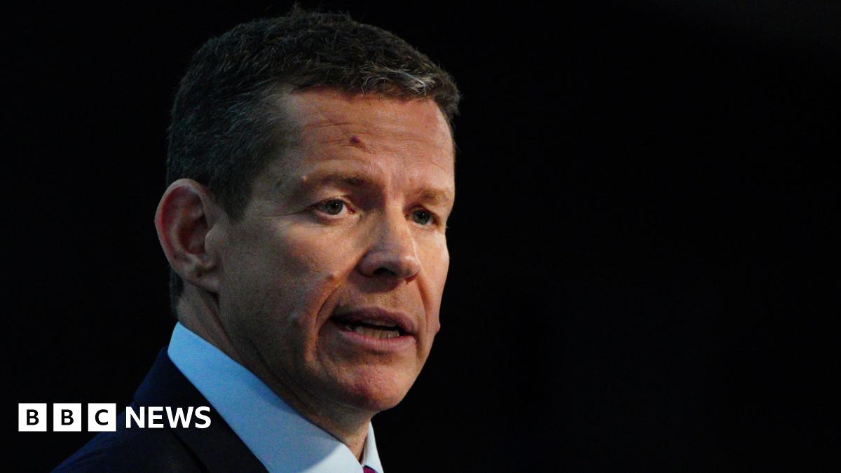 Plaid Cymru leader Rhun ap Iorwerth in front of a dark background, wearing a blue shirt and a red tie.