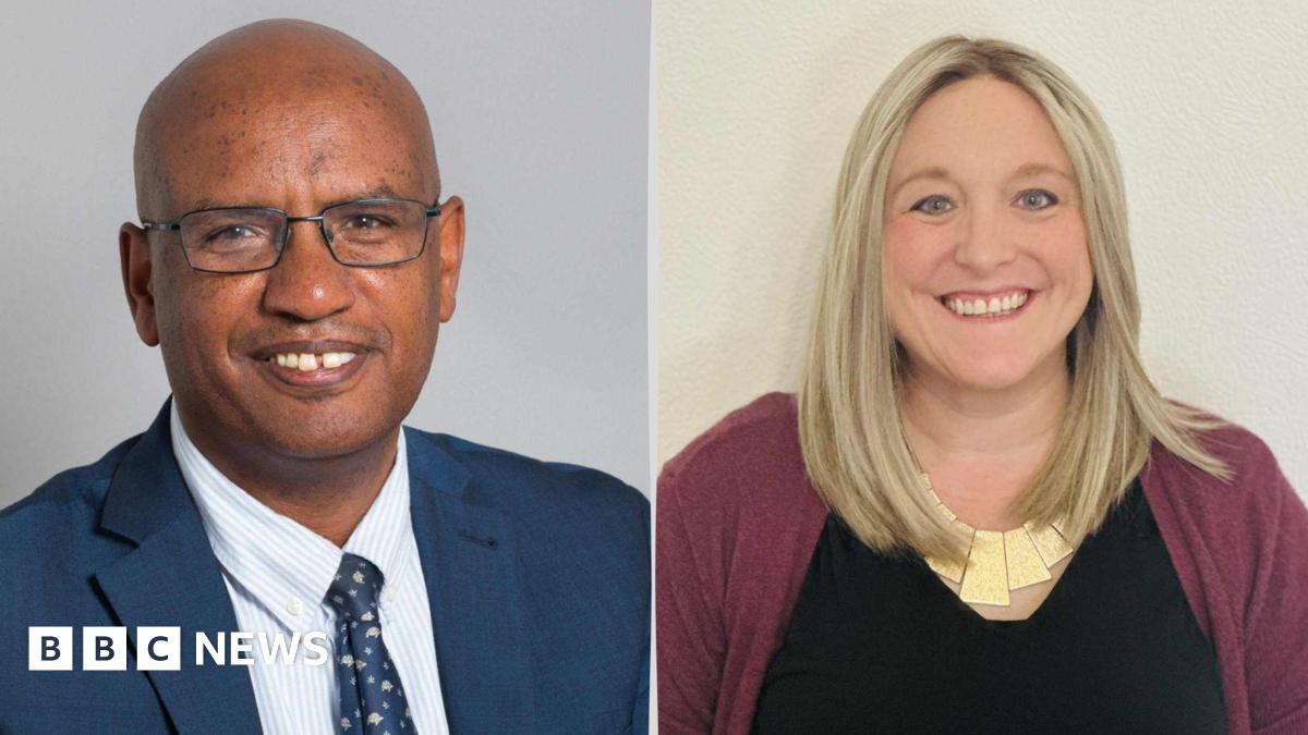 A photo of a man with glasses is wearing a blue suit and blue tie and blue and white striped shirt. There is also a photo of a blonde woman, wearing a purple cardigan and black shirt.