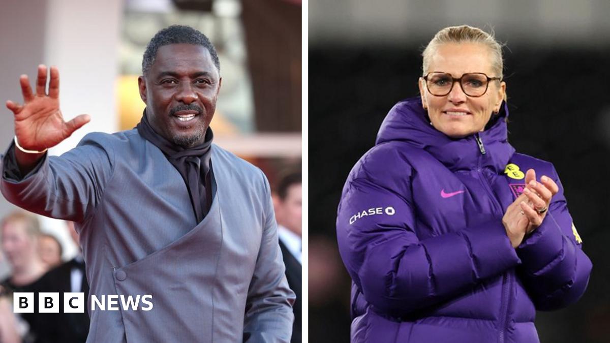 Two individuals shown side by side in separate frames. Idris Elba is wearing a grey suit jacket with a diagonal wrap design and is raising one hand to wave. Sarina Wiegman is wearing a thick purple sports jacket with visible England logos while clapping her hands together.