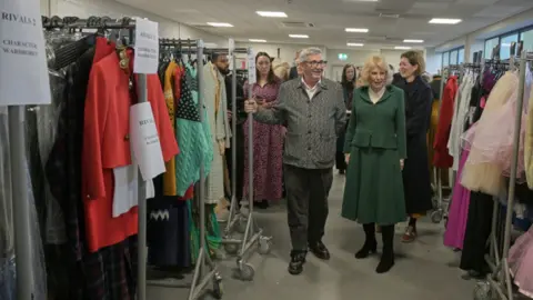PA Queen Camilla looks at the costume department during a visit to the set of the series Rivals in Bristol, to celebrate British television production, youth opportunity in the creative industries, and the legacy of her friend, the author Dame Jilly Cooper.