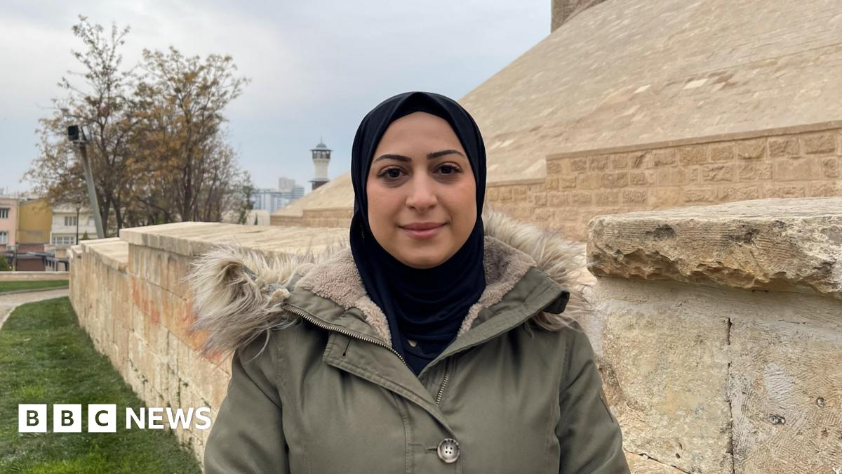 Photo of Aya Mustafa. She is looking directly at the camera wearing a black headscarf and a green winter coat.