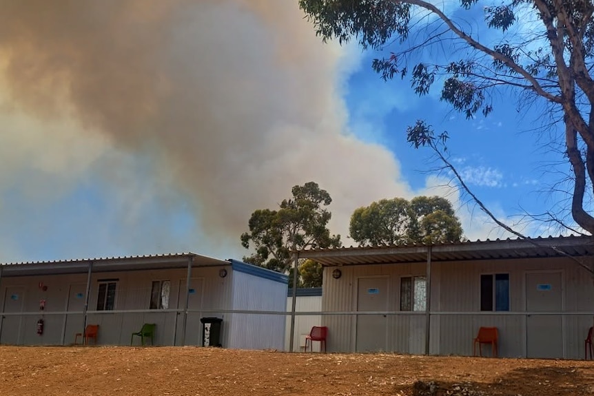 Smoke billows from behind a mine site camp