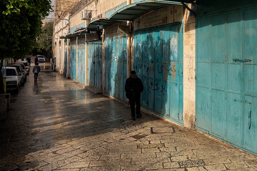 The doors of five shops closed as people walk by on the side walk