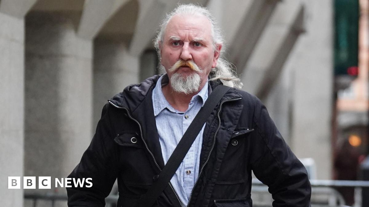 Paul Martin walks to court - seen outside the Old Bailey - wearing a black jacket, light coloured shirt and a cross-body bag. He has long grey hair tied back in a ponytail and a long grey moustache and beard