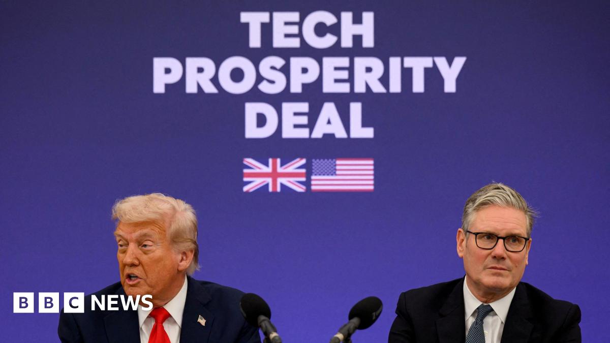 US President Donald Trump and British Prime Minister Keir Starmer seated in front of microphones at a press conference. "Tech Prosperity Deal" is emblazoned in large, white text on a blue backdrop behind them with pictures of UK and USA flags.
