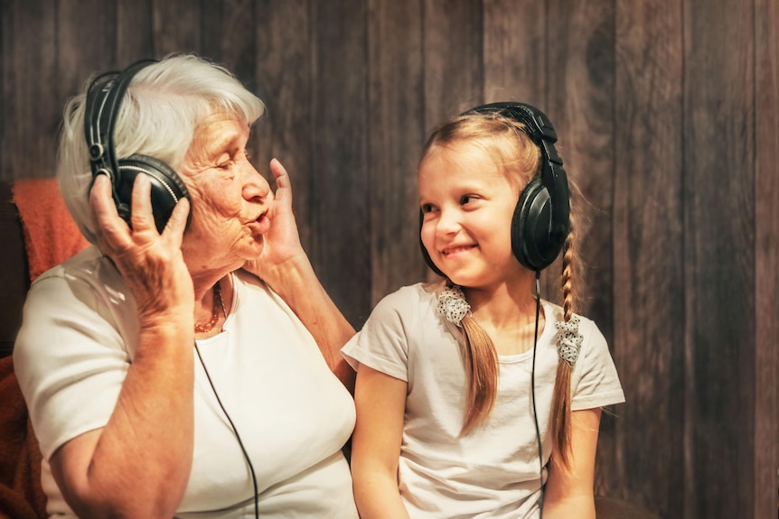 An old woman and a little girl listening to music with headphones