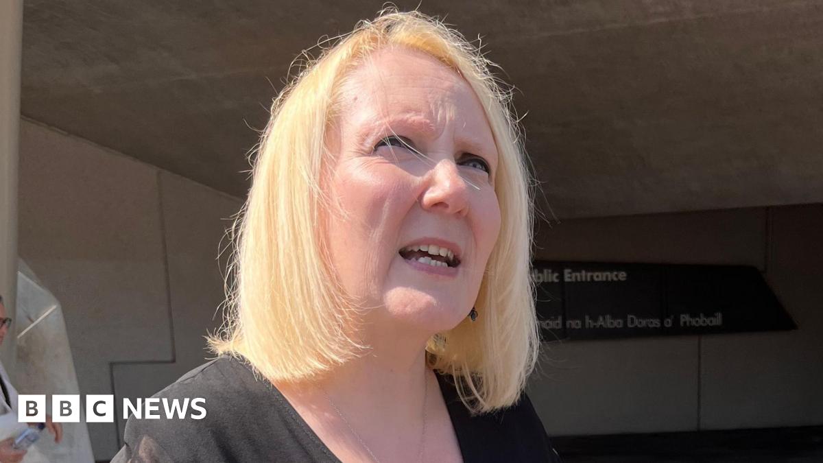 Tressa Burke, who has shoulder length blonde hair looks off into the distance while standing outside the Scottish Parliament building in Edinburgh.