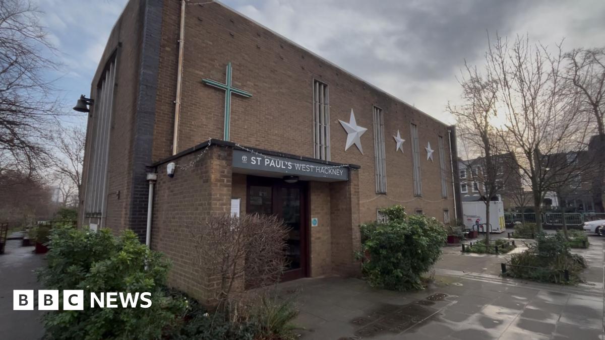 Brick church with silver stars on the outside surrounded by shrubbery.