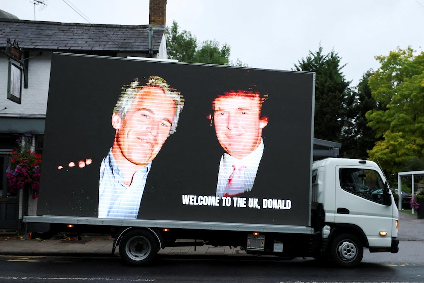 A truck driving down a UK suburban street, hauling a picture of Donald Trump and Epstein together.