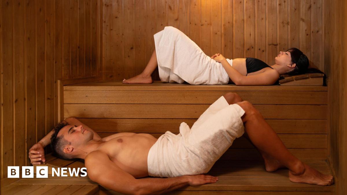 Couple lying on levels in a wooden sauna