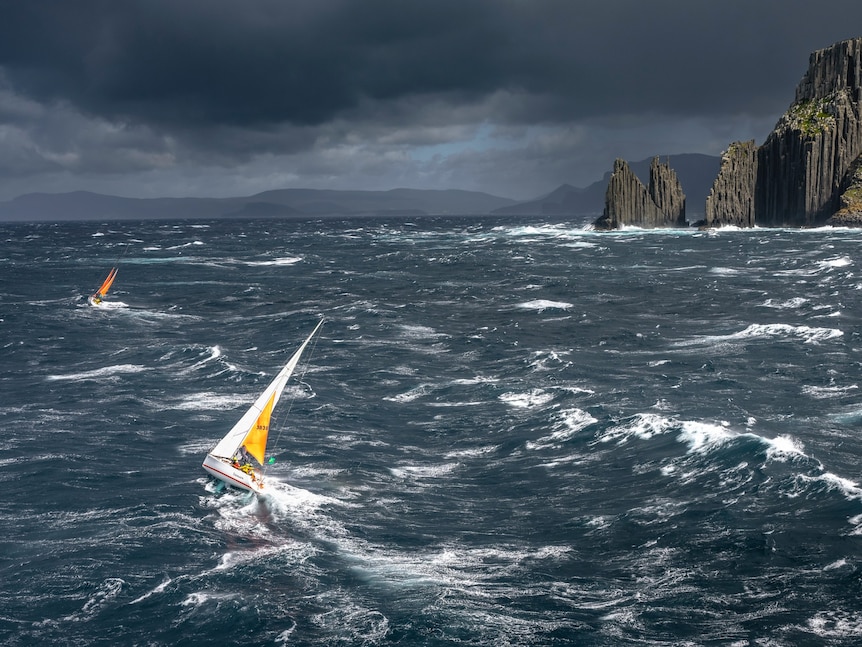 Boats racing near the coast of Tasmania under grey skies.