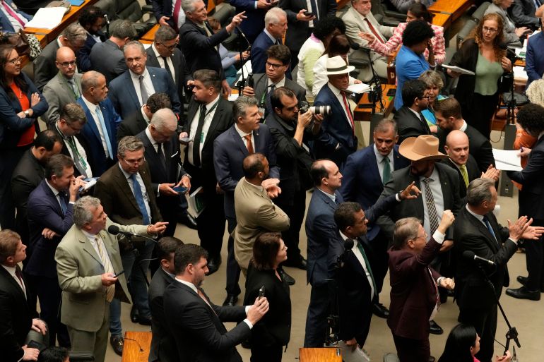 Members of Brazil's Chamber of Deputies standing up on the chamber floor.