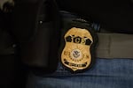 FILE - A federal agent wears a badge of Immigration and Customs Enforcement while standing outside an immigration courtroom at the Jacob K. Javits Federal Building in New York, Tuesday, June 10, 2025.