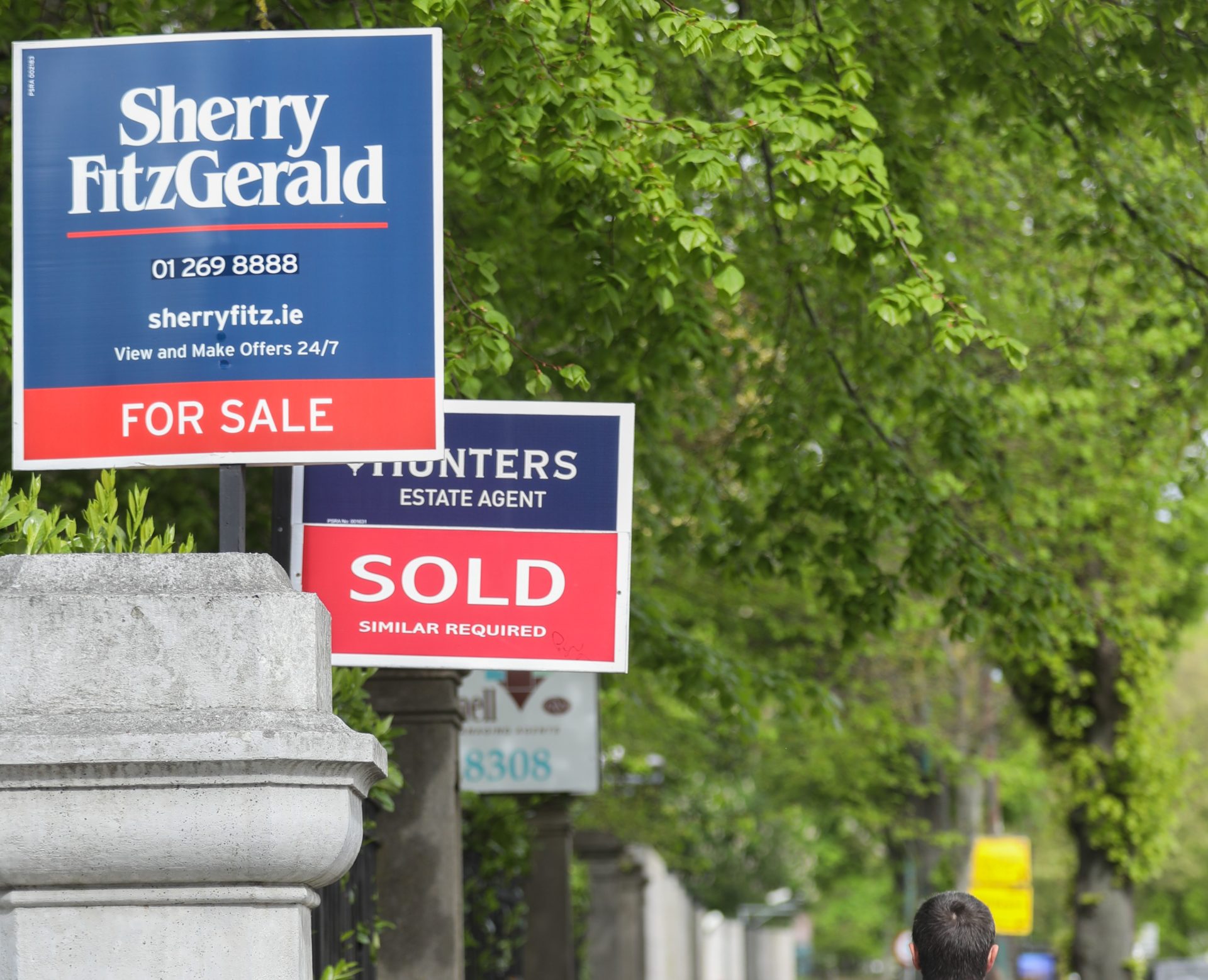 A man walking past 'For Sale' signs in Dublin, 5-5-22.