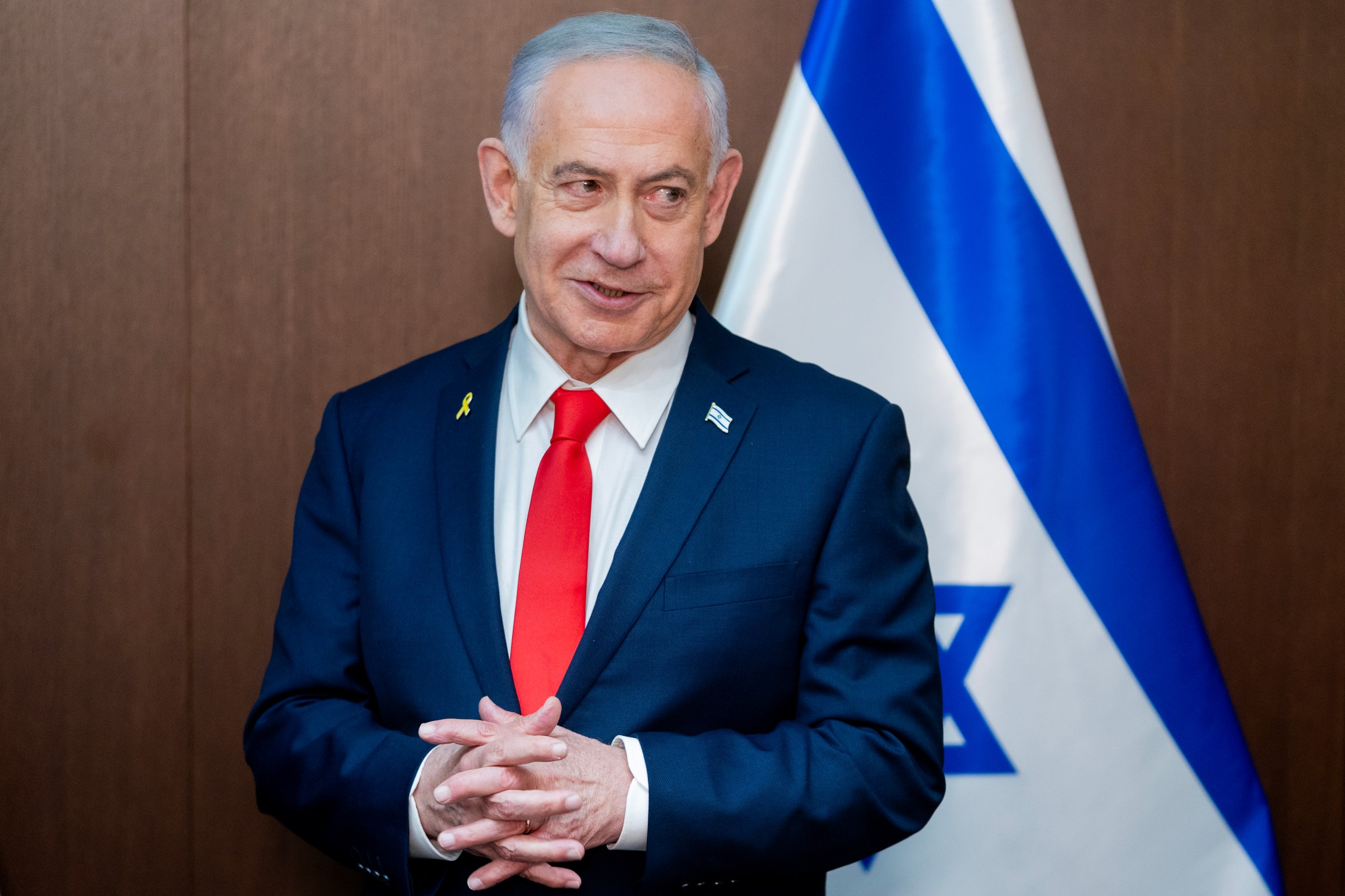 Benjamin Netanyahu standing in front of an Israeli flag.