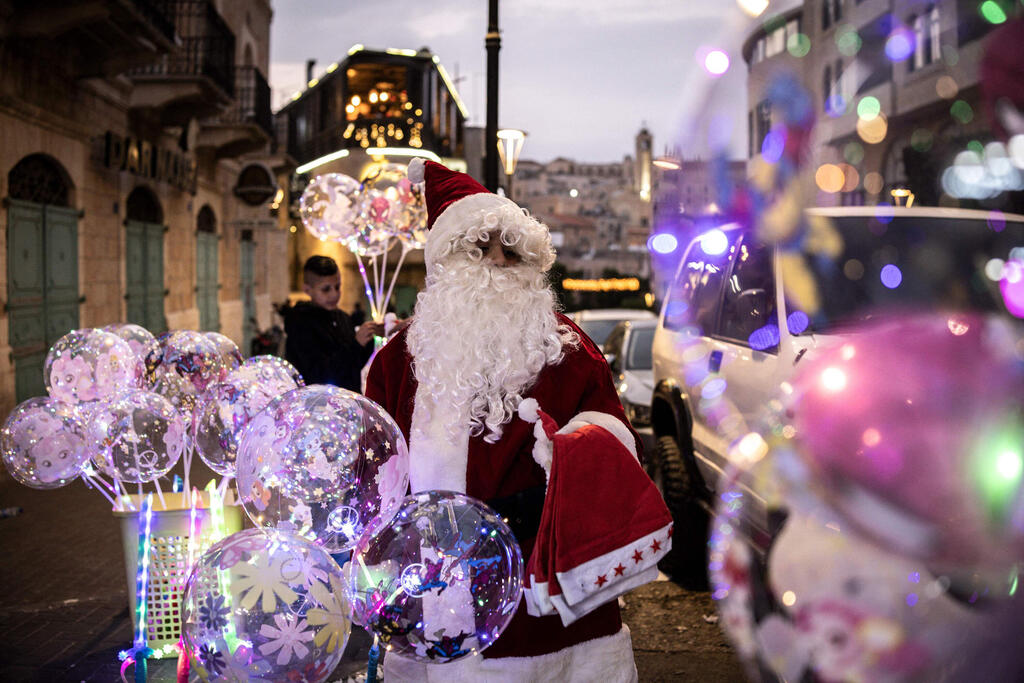 A man dressed as Santa Claus sells balloons near Nativity Square during a Christmas tree lighting ceremony in Bethlehem, West Bank, on December 6, 2025 