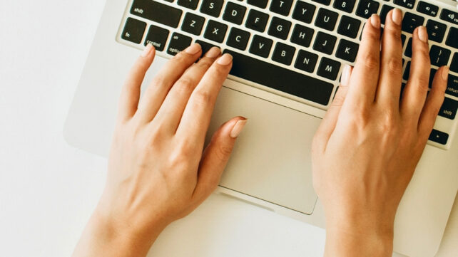 Close image of hands typing on a laptop keyboard