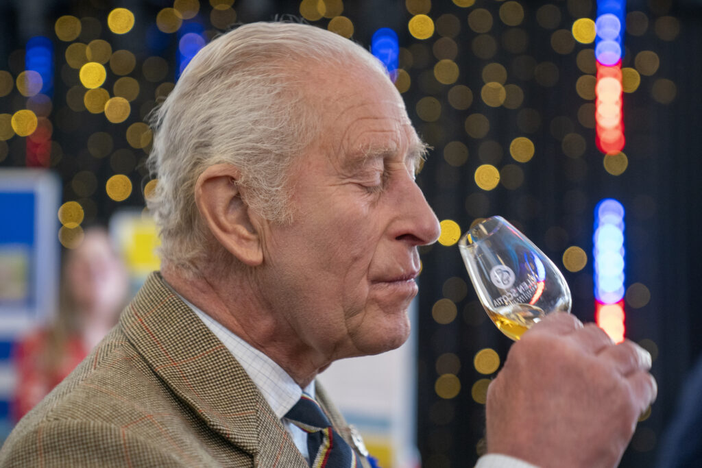 King Charles sniffs a glass of whisky before trying it during a visit to Campeltown in Scotland.