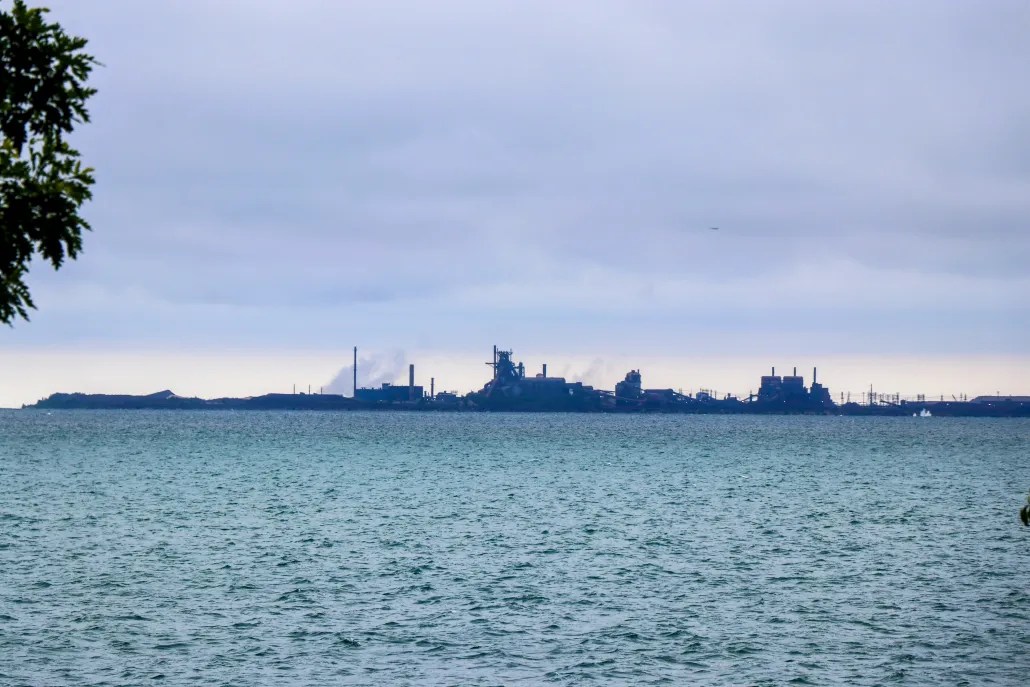 a cloudy Lake Michigan shoreline with smokestacks in the distance